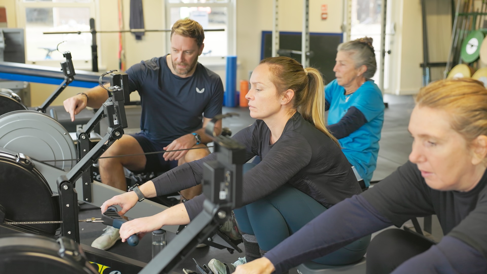 Coach instructing a group of beginners on rowing machines