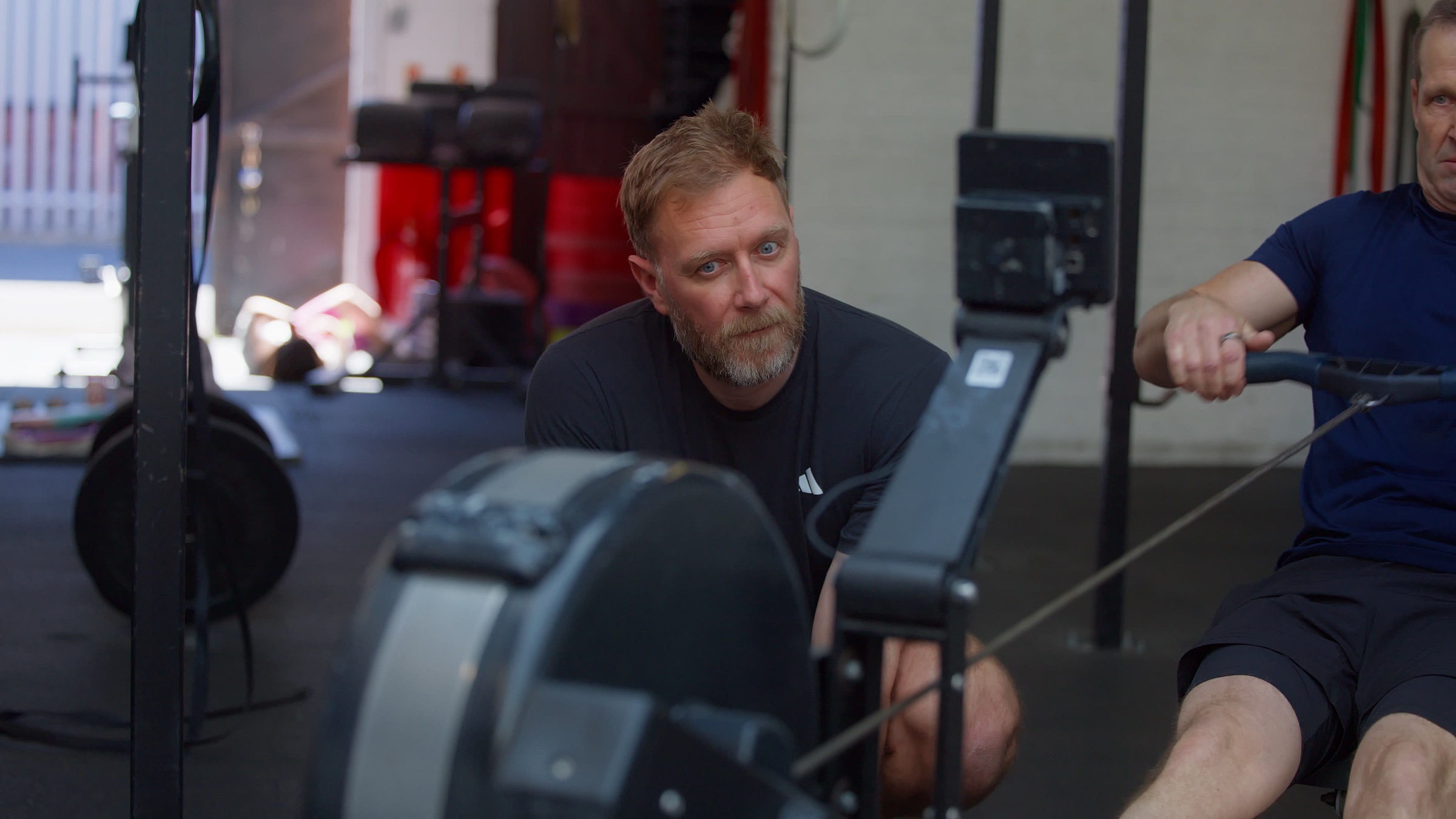 Rob watching a rower closely on the indoor rowing machine