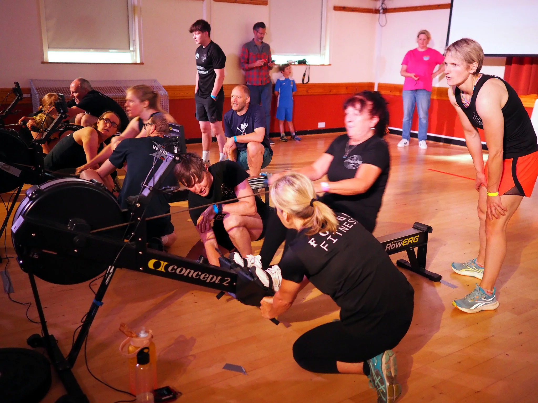 A team crowded around an erg urging on their rower